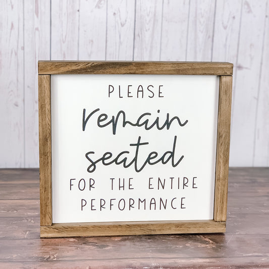 Please remain seated bathroom sign